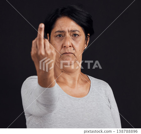Portrait, reject and senior woman with middle finger, opinion and angry expression on a black studio background. Face, female person or elderly model with hand gesture, rude and frustrated with anger Portrait, reject and senior woman with middle finger, opinion and angry expression on a black studio background. Face, female person or elderly model with hand gesture, rude and frustrated with anger 138788896
