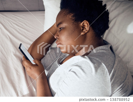 Stress, morning or black woman in bed with phone for social media lying in room for addiction at home. Insomnia, lonely or sad person reading online to scroll on mobile app in bedroom with depression Stress, morning or black woman in bed with phone for social media lying in room for addiction at home. Insomnia, lonely or sad person reading online to scroll on mobile app in bedroom with depression 138788952