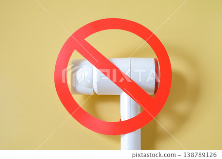 Hair dryer with prohibition sign on color background. Hair dryer with prohibition sign on color background. 138789126