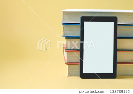 Tablet on hard cover book on color background. 138789155