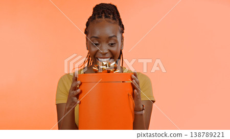 Birthday, present and black woman with surprise, box or gift in studio background or celebration. Wow, congratulations and excited winner of giveaway, package or product on offer for party and event Birthday, present and black woman with surprise, box or gift in studio background or celebration. Wow, congratulations and excited winner of giveaway, package or product on offer for party and event 138789221