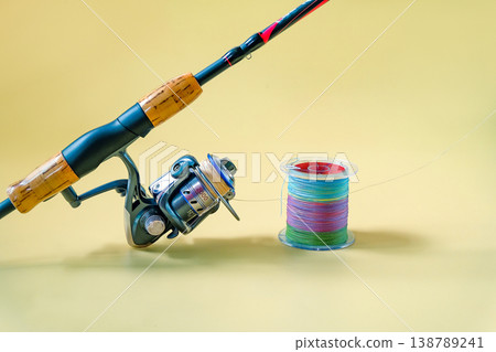 Fishing rod spinning with the line on color background. Fishing rod spinning with the line on color background. 138789241
