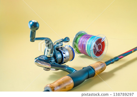 Fishing rod spinning with the line on color background. Fishing rod spinning with the line on color background. 138789297