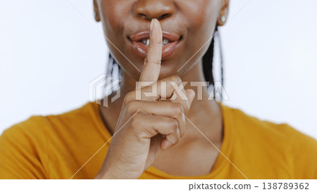 Secret, finger to lips and black woman in studio for privacy, confidential information and face on white background. Mouth zoom, quiet and silence gesture with emoji, gossip or whisper with news 138789362