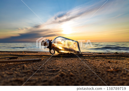Message in glass bottle on sandy beach at sunset. 138789719