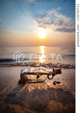 Message in glass bottle on sandy beach at sunset. 138789721