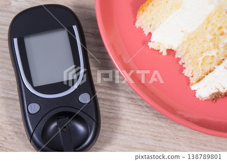 Glucose meter for measuring sugar level and piece of sweet cake with chocolate Glucose meter for measuring sugar level and piece of sweet cake with chocolate 138789801
