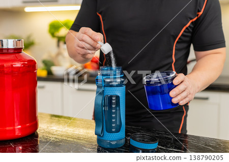 Asian man mixing supplement powder in shaker bottle shaking electrolyte recovery drink at home gym 138790205