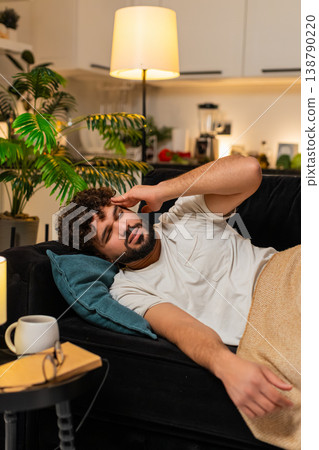 Arabian man lies with strong headache holds head at temple closes eyes feels pain needs rest tonight Arabian man lies with strong headache holds head at temple closes eyes feels pain needs rest tonight 138790220