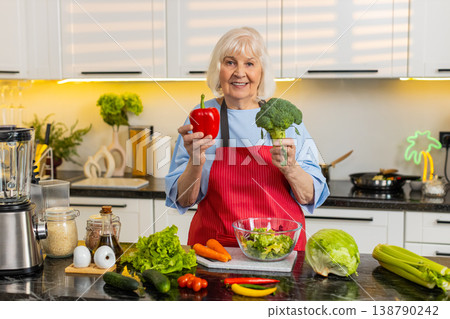 Senior old woman smiling in kitchen choosing fresh vegetables for healthy diet and home cooking meal Senior old woman smiling in kitchen choosing fresh vegetables for healthy diet and home cooking meal 138790242