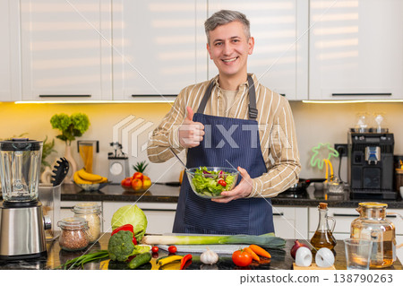 Middle-aged man showing fresh vegetable salad with thumbs up in kitchen for healthy eating routine 138790263