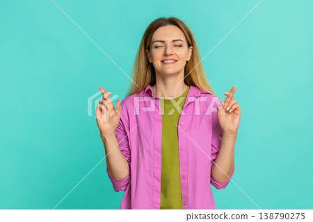 Woman crossing fingers with closed eyes expressing hope desire or silent wish with emotional focus Woman crossing fingers with closed eyes expressing hope desire or silent wish with emotional focus 138790275