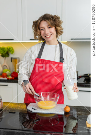Young woman redhead happy whisking eggs with milk in kitchen for healthy diet breakfast prep at home 138790296