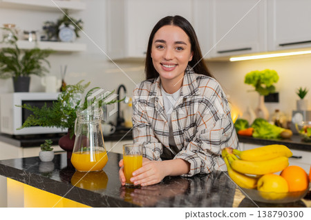 Young woman drinks fresh orange juice from glass, enjoying healthy hydration in home kitchen 138790300