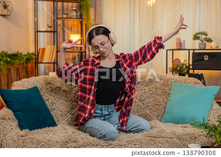 Woman dancing to favorite music at home with energy, smiling moving with positive joyful expression 138790308