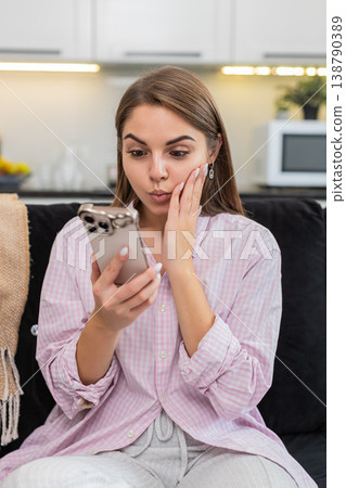 Young woman reacts wow eyes wide holding smartphone to positive big surprise and news about game win 138790389