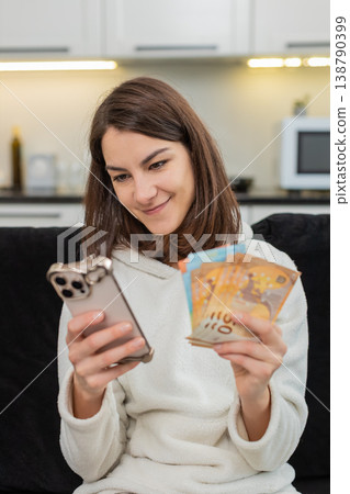 Woman counts euro money cash checks rate on smartphone smiles plans dream buy salary savings bonus Woman counts euro money cash checks rate on smartphone smiles plans dream buy salary savings bonus 138790399