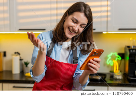 Young woman smiling using smartphone in home kitchen enjoying break during healthy meal prep routine Young woman smiling using smartphone in home kitchen enjoying break during healthy meal prep routine 138790400