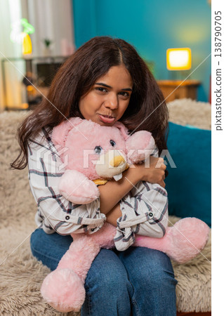 Indian woman holding pink bunny toy smiling nostalgic memory emotion missing childhood child indoors 138790705