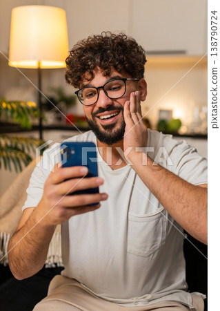 Arabian man celebrates online game jackpot win after good news alert on smartphone at night indoors Arabian man celebrates online game jackpot win after good news alert on smartphone at night indoors 138790724