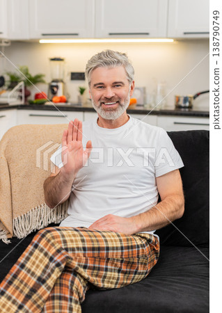 Middle-aged man waves to camera smiles hello online connection greets viewer friendly positive mood Middle-aged man waves to camera smiles hello online connection greets viewer friendly positive mood 138790749