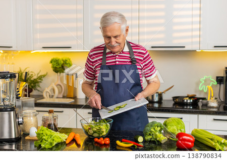 Senior old man mixing cucumber salad in home kitchen for diet plan and healthy nutrition lifestyle 138790834