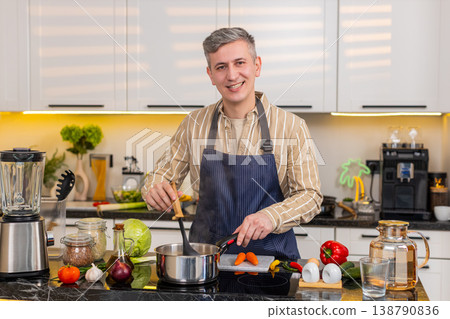 Middle-aged man cooking fresh diet soup in kitchen smelling aroma and tasting healthy homemade meal Middle-aged man cooking fresh diet soup in kitchen smelling aroma and tasting healthy homemade meal 138790836