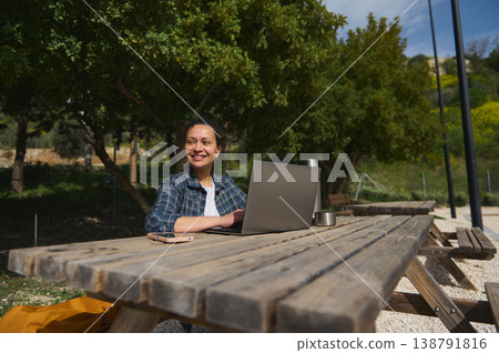 Happy woman working on laptop outdoors, enjoying remote lifestyle Happy woman working on laptop outdoors, enjoying remote lifestyle 138791816