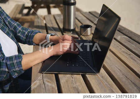 Close up of hands typing on laptop outdoors, remote work concept. Side view Close up of hands typing on laptop outdoors, remote work concept. Side view 138791819