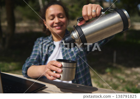 Close up of pouring hot drink from thermos into cup outdoors Close up of pouring hot drink from thermos into cup outdoors 138791825