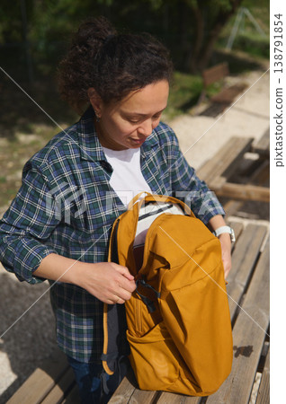 Woman putting thermos into backpack close-up Woman putting thermos into backpack close-up 138791854