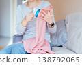 Close up female hands using electric fabric shaver on pink knitwear. Unrecognizable woman removing pills from textile, clothing care routine, home maintenance, soft fabric detail. 138792065