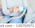 Close up of unrecognizable woman in striped shirt using fabric shaver on gray knitted sweater while sitting at home. Domestic clothing care, garment maintenance, pilling removal, cozy everyday routine 138792072