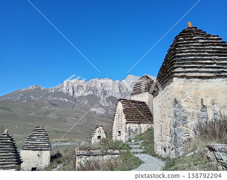 View of Dargavs necropolis, known as City of the Dead, North Ossetia, Russia. Stone mausoleums with traditional architecture on a sunny hillside View of Dargavs necropolis, known as City of the Dead, North Ossetia, Russia. Stone mausoleums with traditional architecture on a sunny hillside 138792204