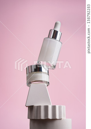 Anti-age serum and eye cream bottles on white stands with pink background Anti-age serum and eye cream bottles on white stands with pink background 138792283
