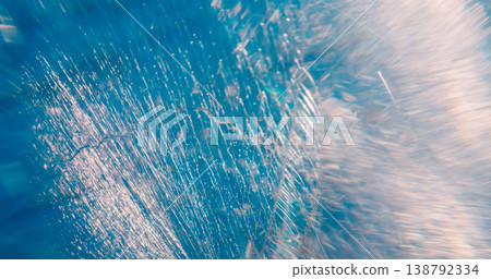 Defocused scratched lens. Old glass texture. Cracked prism on illuminated color abstract background. Blue white art light aged beam. Defocused scratched lens. Old glass texture. Cracked prism on illuminated color abstract background. Blue white art light aged beam. 138792334