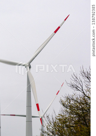 wind turbines in field rotate their blades to generate energy. windmill on spacious green field. 138792385