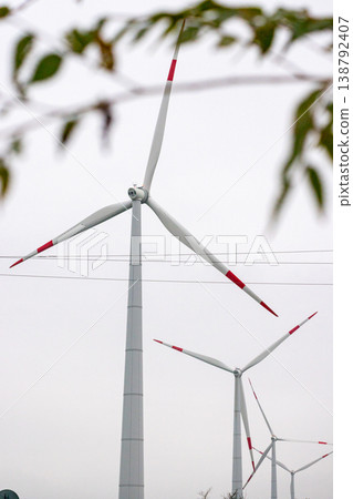 wind turbines in field rotate their blades to generate energy. windmill on spacious green field. wind turbines in field rotate their blades to generate energy. windmill on spacious green field. 138792407