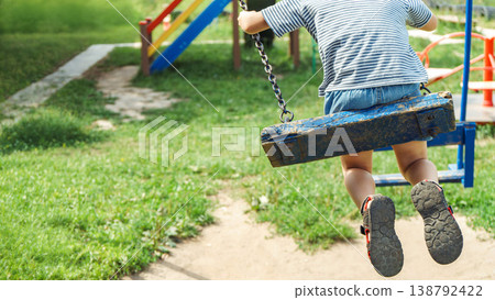 Boy captured in candid moment swinging as background features vibrant playground scene Boy captured in candid moment swinging as background features vibrant playground scene 138792422