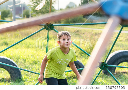 Boy looks up intently at climbing frame, ready to climb Boy looks up intently at climbing frame, ready to climb 138792503