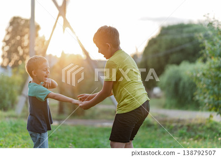 Older boy guiding younger in park play, supportive handhold and encouraging posture 138792507