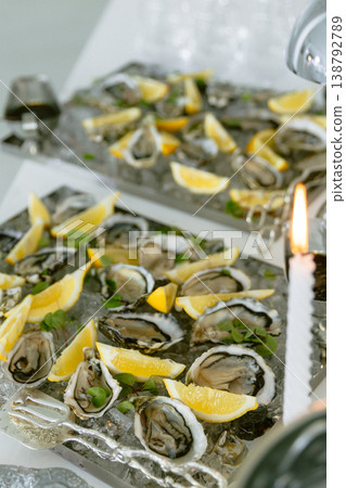 Oysters served on ice with lemon slices at elegant seafood reception. Oysters served on ice with lemon slices at elegant seafood reception. 138792789
