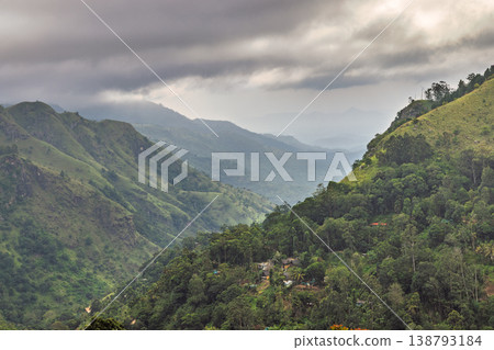 Dramatic Mountain Landscape with Lush Green Valleys and Overcast Sky, Showcasing Serene Natural Beauty and Remote Living. Mountain landscape near Ella in Sri Lanka. Dramatic Mountain Landscape with Lush Green Valleys and Overcast Sky, Showcasing Serene Natural Beauty and Remote Living. Mountain landscape near Ella in Sri Lanka. 138793184