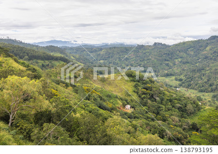 Verdant Mountain Landscape with Scattered Trees and Distant Peaks Under a Cloudy Sky, Nature's Grandeur. Mountain landscape near Ella town in Sri Lanka island in Asia. Verdant Mountain Landscape with Scattered Trees and Distant Peaks Under a Cloudy Sky, Nature's Grandeur. Mountain landscape near Ella town in Sri Lanka island in Asia. 138793195