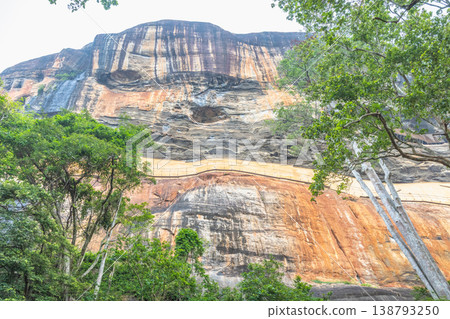 Sigiriya ancient rock fortress in Sri Lanka. Majestic Textured Rock Formation Adorned with Lush Green Foliage Under a Bright Sky, Natural Outdoor Scenery Sigiriya ancient rock fortress in Sri Lanka. Majestic Textured Rock Formation Adorned with Lush Green Foliage Under a Bright Sky, Natural Outdoor Scenery 138793250