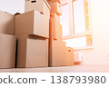 Cardboard boxes are piled high in a bright room 138793980