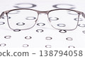 Silver-framed eyeglasses sit atop a visual acuity chart 138794058