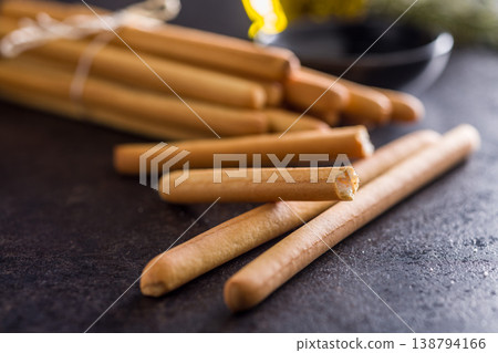 Bundled Italian Breadsticks (Grissini) with Olive Oil and Rosemary on Dark Surface 138794166