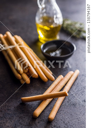 Bundled Italian Breadsticks (Grissini) with Olive Oil and Rosemary on Dark Surface 138794167