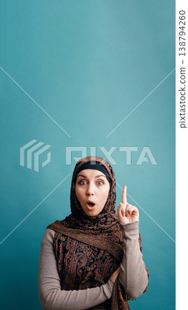 Muslim woman having an idea pointing finger up 138794260